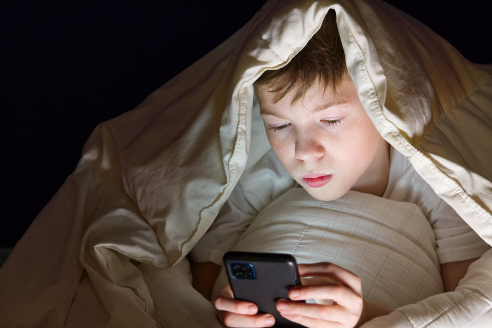 Teen checking phone at night maintaining Snapchat streak